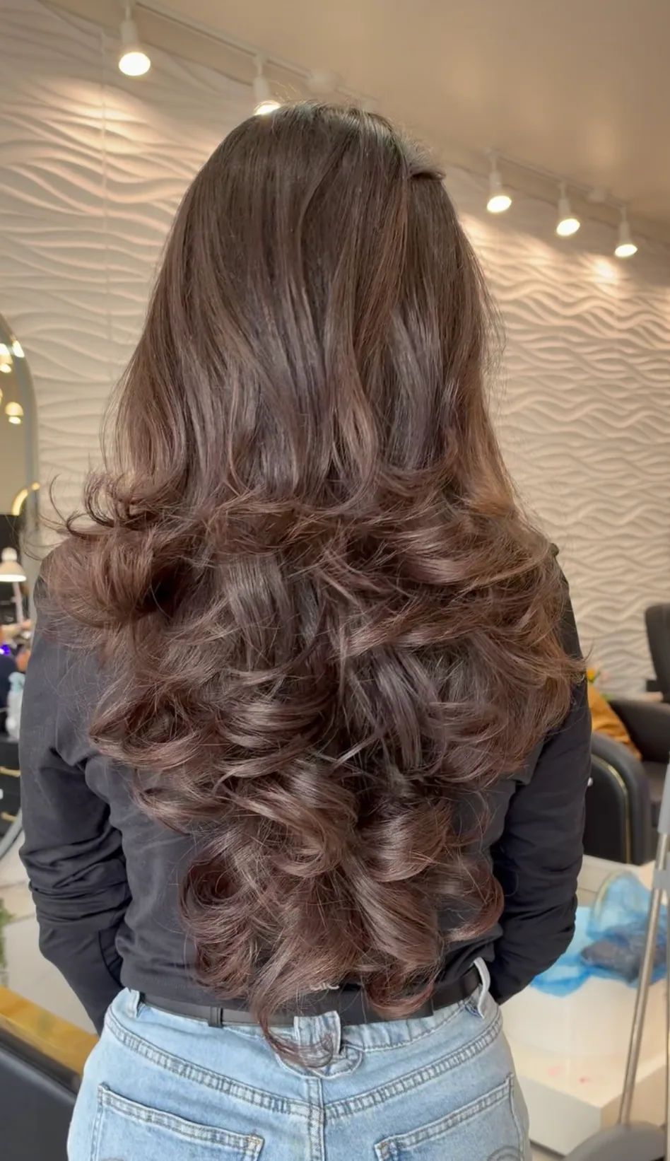 Long brunette hair styled in voluminous curls, seen from behind